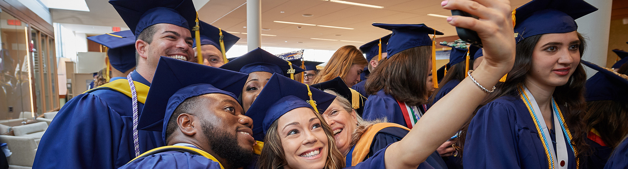 Students dressed in graduation robes take a selfie