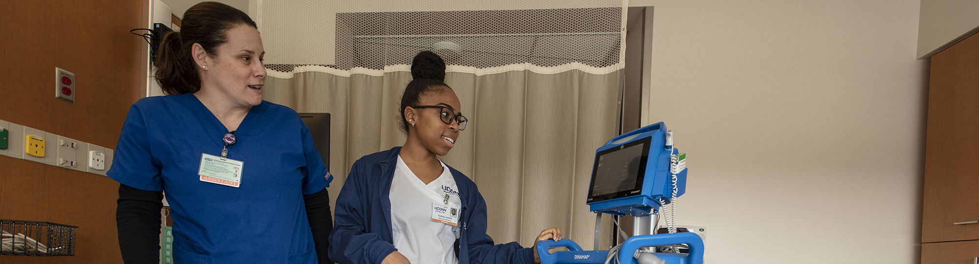 A student checks a monitor in a patient's room