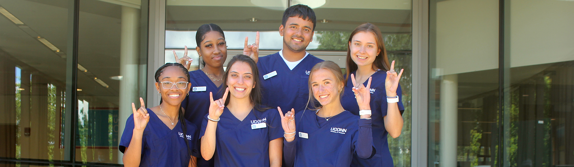 A group of six students wearing blue scrubs.
