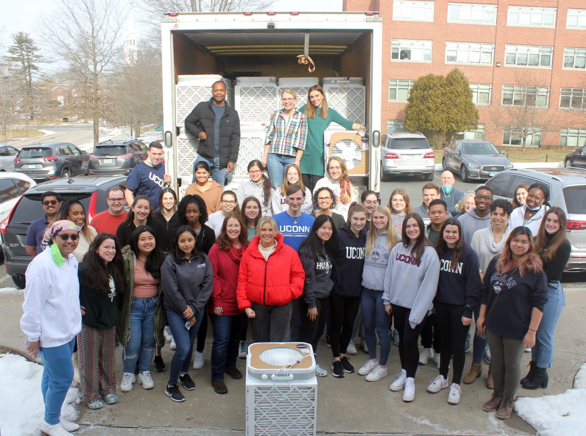 A group of students and faculty pose in front of a truck filled with DIY air purifiers.